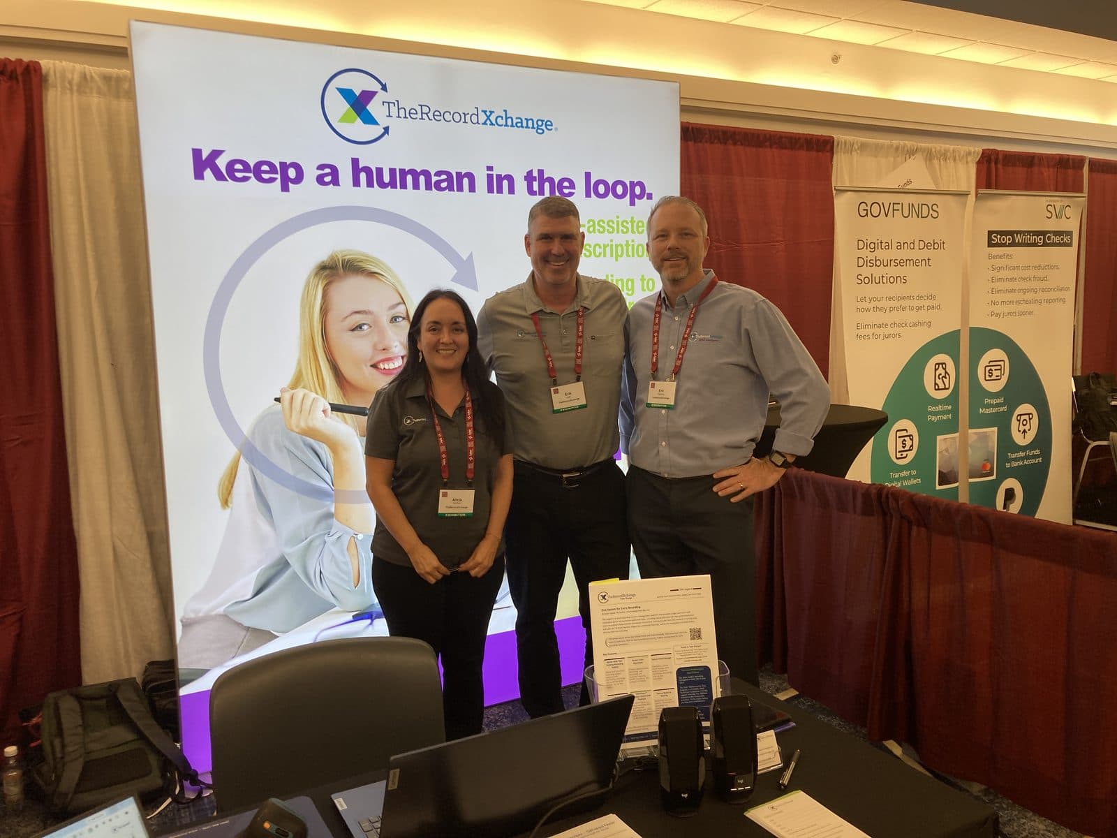 Three members of the TheRecordXchange team at the NACM Annual Conference, in front of the TRX 'Keep a human in the loop' banner
